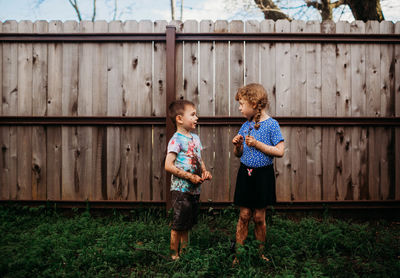 Two young kids standing outside talking covered in mud