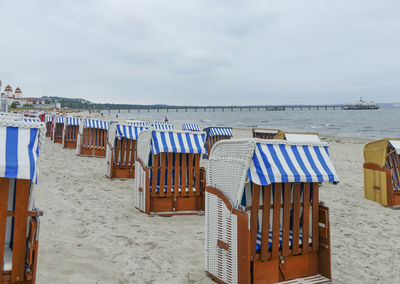 Hooded chairs on beach against sky