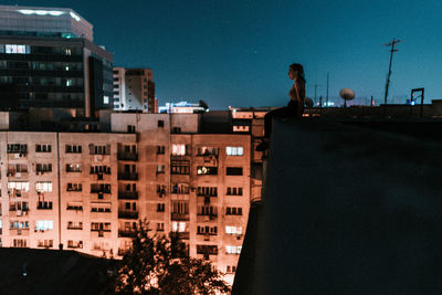 Full length of woman sitting on building terrace