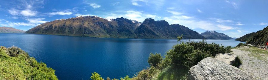 Panoramic view of lake and mountains against blue sky