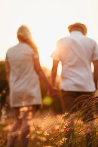 Rear view of people walking against sky during sunset