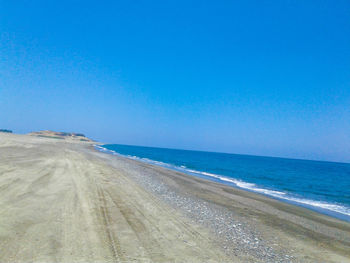 Scenic view of beach against clear blue sky