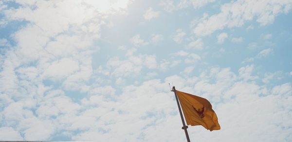 Low angle view of flag flying against sky