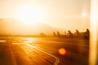 Airplanes at airport against sky during sunset