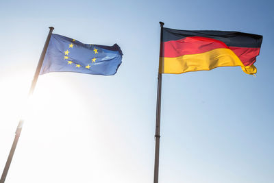 Low angle view of german and european union flags against sky