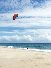 View of parachuting on beach against clouds