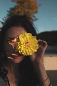 Close-up portrait of woman holding yellow flower and crystal