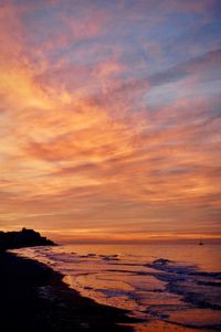 Scenic view of sea against dramatic sky during sunset