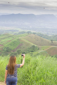 Rear view of woman photographing on landscape