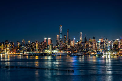Illuminated buildings against blue sky at night