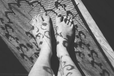 Low section of woman with shadow standing on hardwood floor in darkroom