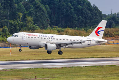 Airplane flying over airport runway against sky