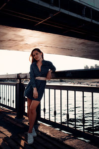 Full length of woman standing against railing