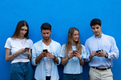 Group of people looking away while standing on blue wall