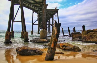 Wooden posts on beach against sky