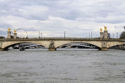 Bridge over river in city against sky