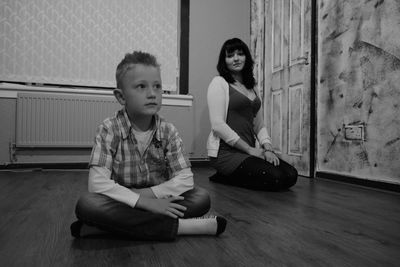 Mother looking at son while sitting on floor