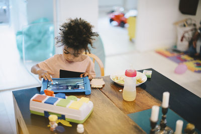 Boy using digital tablet while sitting at table