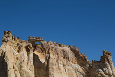 Low angle view of rock formations against clear blue sky