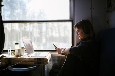 Female professional text messaging through smart phone while traveling in train