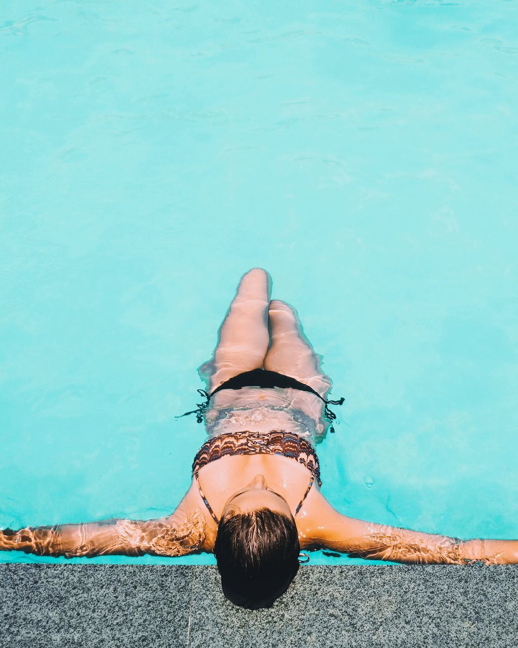 one person, water, lifestyles, leisure activity, swimming pool, nature, real people, pool, sea, blue, relaxation, clothing, lying down, young adult, day, high angle view, swimwear, outdoors, turquoise colored