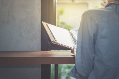 Midsection of woman reading file while sitting at table