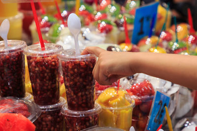 Child's hand pointing to plastic jar with fruits