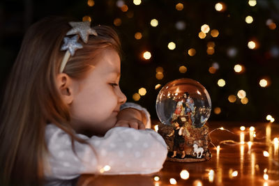 Girl looking at a glass ball with a scene of the birth of jesus christ