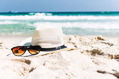 Sunglasses on beach by sea against sky