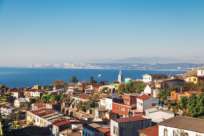 High angle view of townscape by sea against clear blue sky