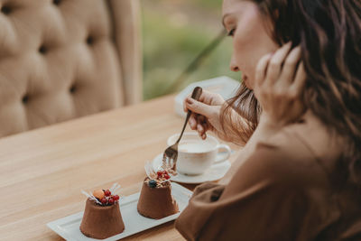 Midsection of woman holding drink sitting on table