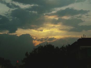 Low angle view of silhouette trees and buildings against sky during sunset