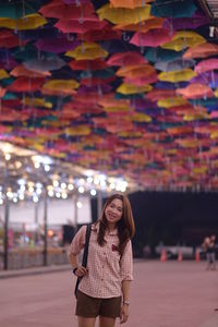 Smiling young woman standing against building