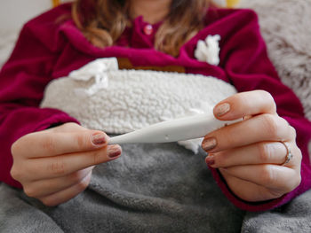 Midsection of woman holding thermometer