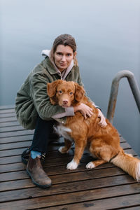 Portrait of young woman with dog on pier