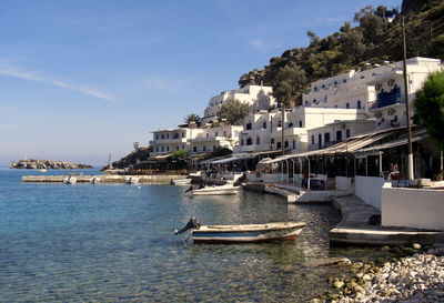 Boats in sea by town against sky