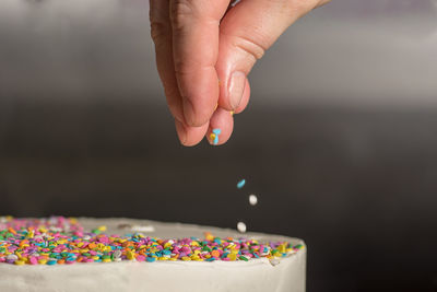 Pastry chef adding sprinkles to a birthday cake.