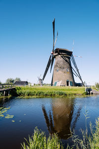 Reflection of traditional windmill on lake against sky