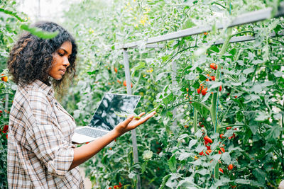 Young woman standing against plants