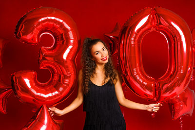 Young adult woman on the background of red balloons