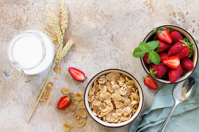 Healthy breakfast - whole grain flakes, milk and fresh strawberries on stone or slate background.