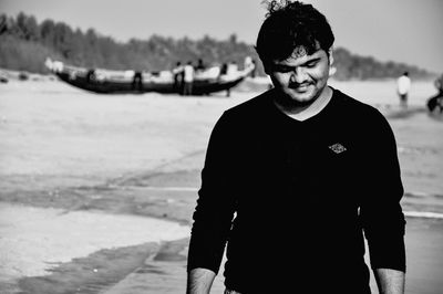 Smiling young man standing on sea shore