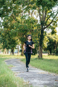 Full length portrait of young woman on footpath