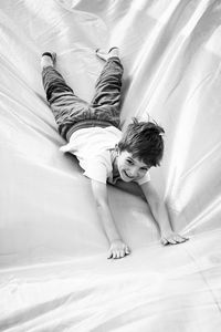 High angle view of boy lying on textile