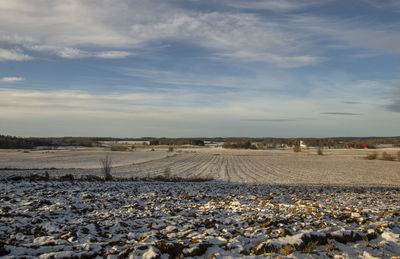 Scenic view of lightly snow covered landscape against clouded sky 