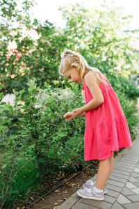 Side view of young woman standing on footpath