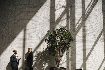 Businessmen discussing while standing by wall during networking event at convention center