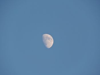 Low angle view of moon against clear blue sky