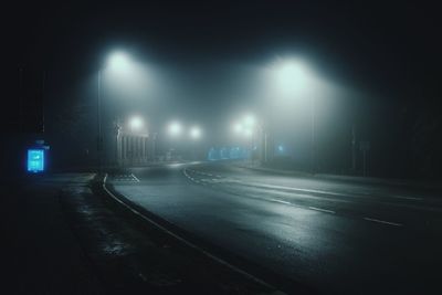 Illuminated street lights on road in city at night