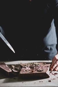 Midsection of chef cutting chocolate at table